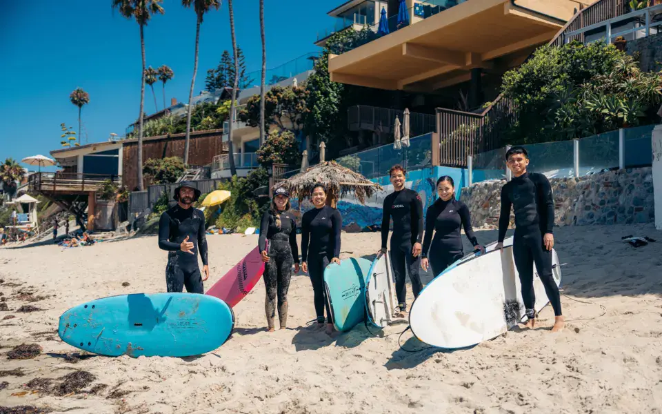 Groupe de surfeurs en combinaison sur la plage avec des planches