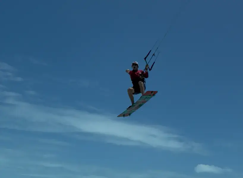 Kitesurfeur en plein saut sous un ciel bleu