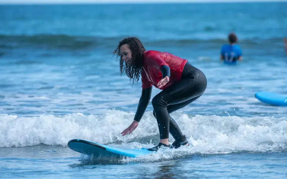 Surfeuse debout sur sa planche dans une vague