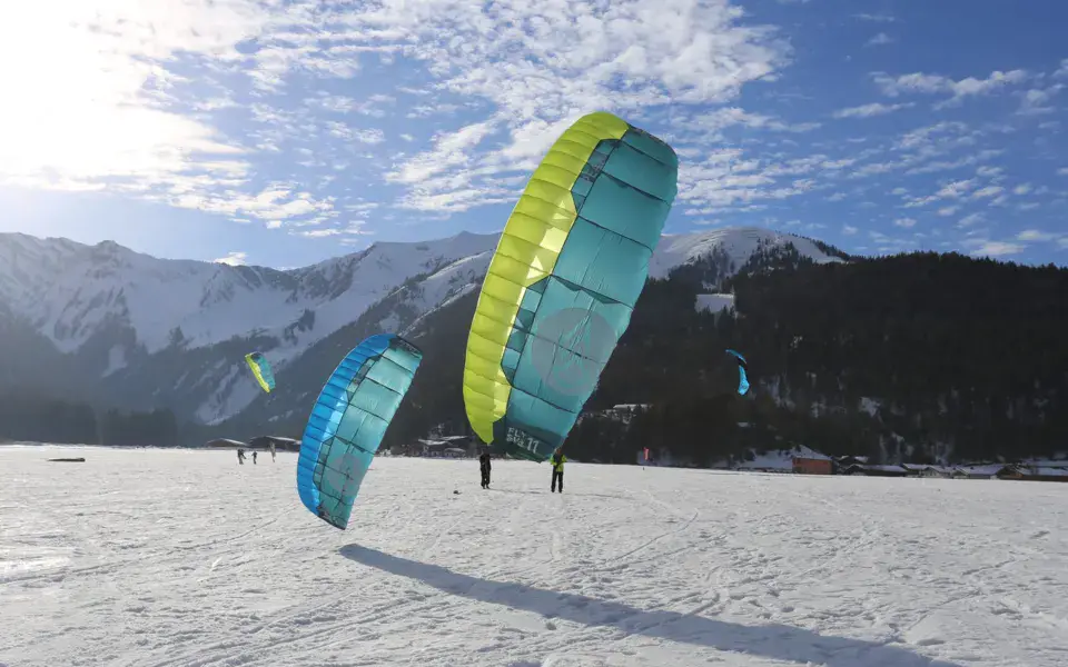 Deux ailes de snowkite sur le lac gelé, avec les montagnes en arrière-plan