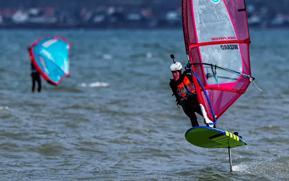 Windsurfeur sur un foil, un kite à l'arrière-plan
