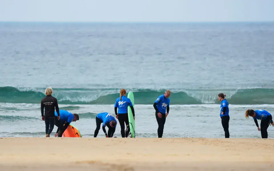 Groupe en combinaisons bleues sur la plage avant un cours de surf