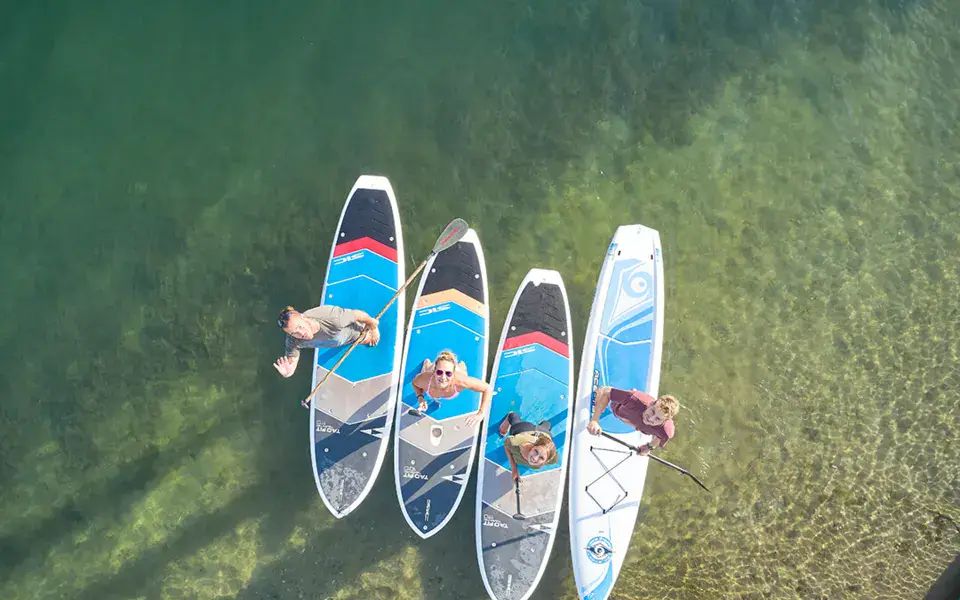 Quatre paddleurs vus du ciel sur une eau claire