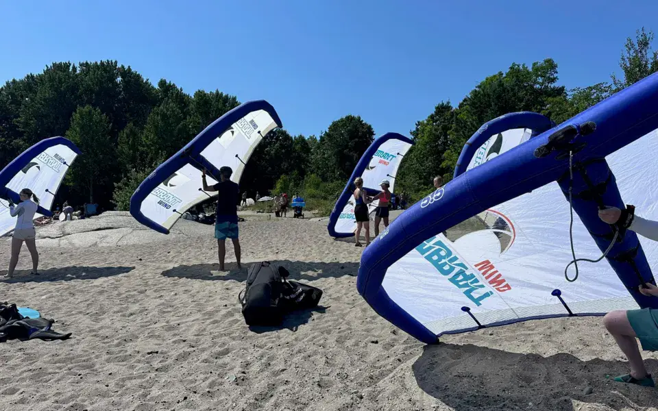 Groupe de participants avec leurs ailes de wing foil sur une plage de sable