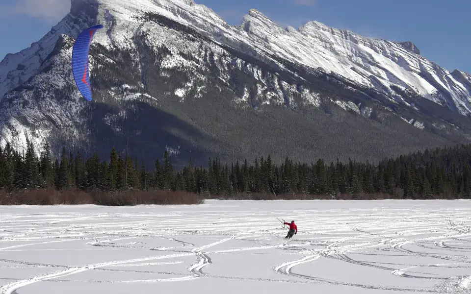 Snowkite sur un lac gelé au pied d'une montagne enneigée