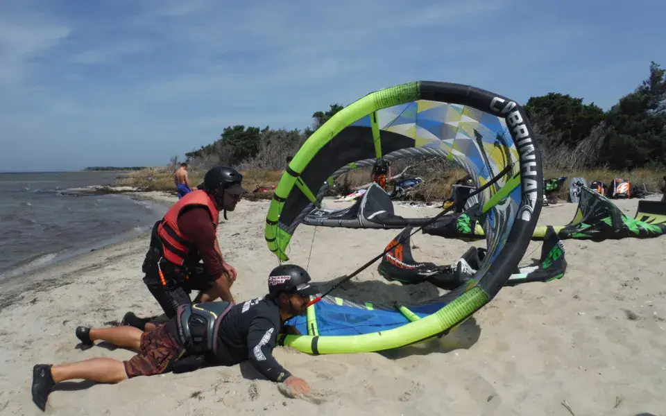 Moniteur aidant un élève avec son aile sur la plage