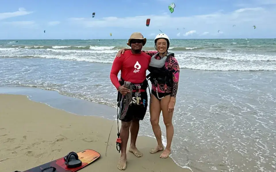 Un moniteur et une élève sur la plage, kites dans le ciel derrière eux