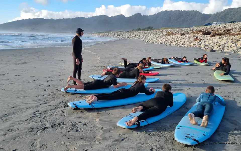 Élèves allongés sur leur planche pour l'échauffement sur la plage