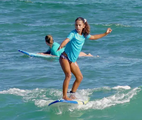 Jeune élève debout sur sa planche pendant un cours de surf