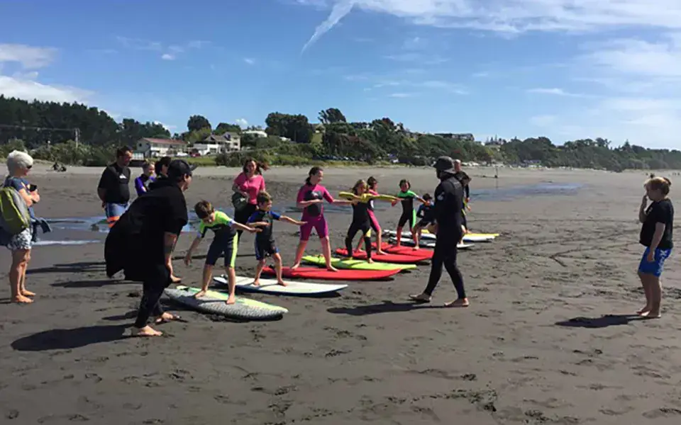 Groupe de cours de surf sur la plage, planches alignées sur le sable