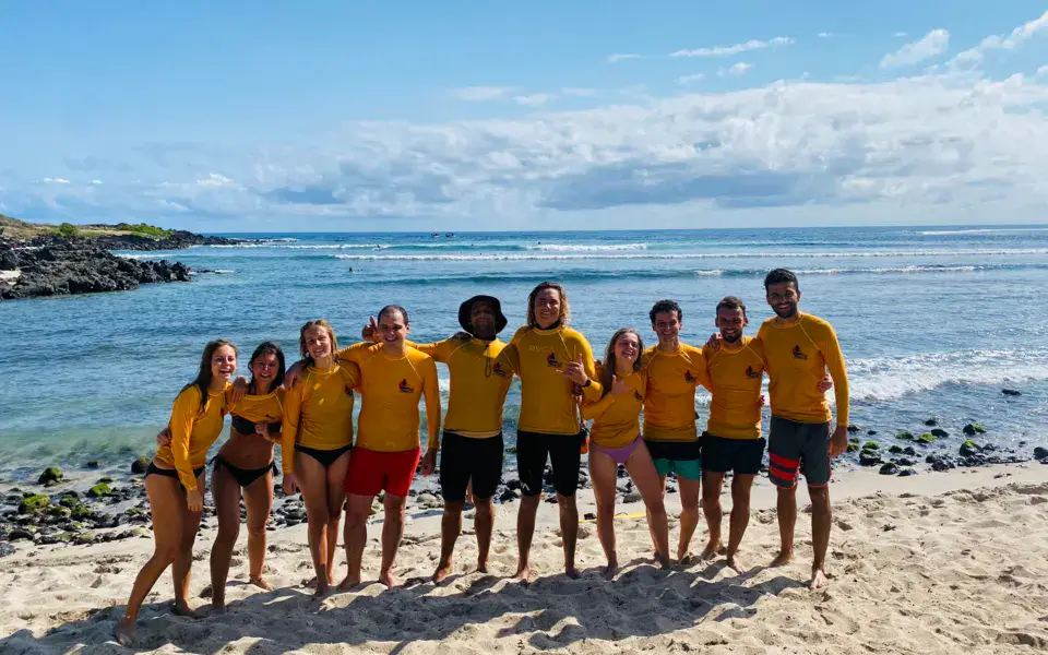 Équipe de l'école en rashguard jaune sur la plage