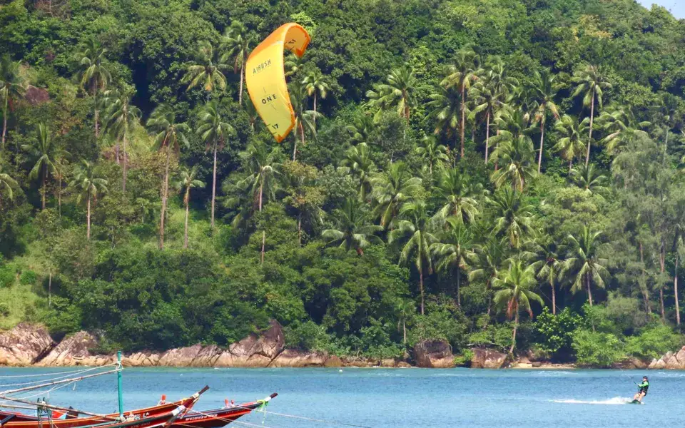 Un kitesurfeur devant des pirogues de pêcheurs
