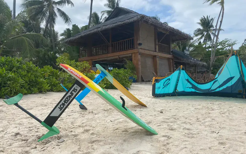 Matériel de kite et de foil sur la plage, devant le bâtiment du centre