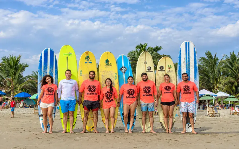 L'équipe de moniteurs alignée sur la plage devant les planches