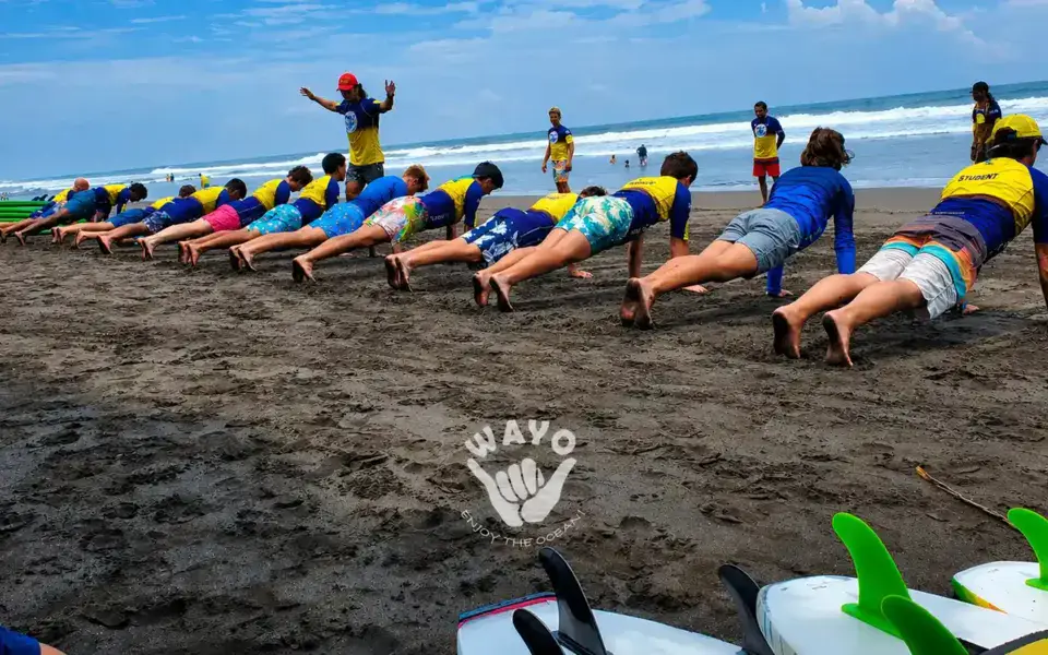 Échauffement d'un groupe d'élèves sur le sable avant le cours