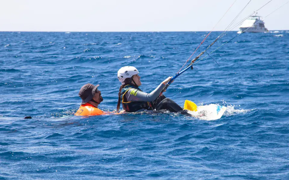 Cours de kitesurf dans l'eau avec un moniteur, bateau d'assistance au fond