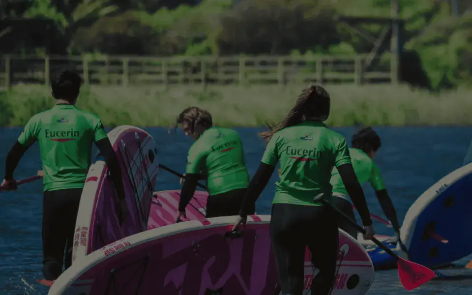 Groupe en t-shirts verts portant des planches de paddle au bord d'un plan d'eau