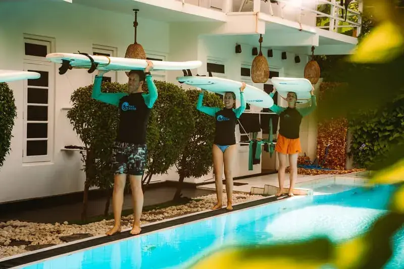 Surfeurs avec leurs planches au bord de la piscine du camp