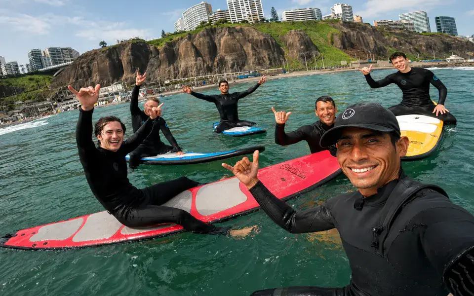 Cours collectif de surf sur l'eau, avec les falaises de Miraflores en arrière-plan