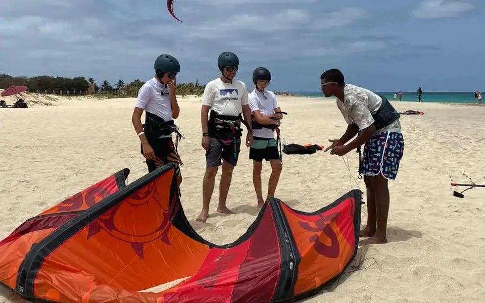 Briefing d'un moniteur avant le cours, avec une aile posée sur le sable